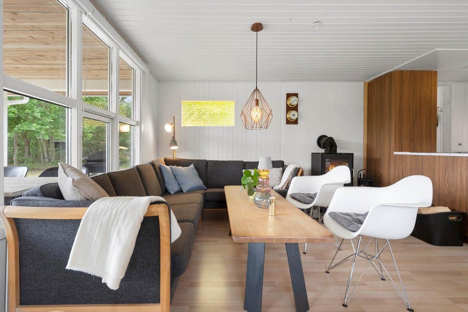Wohnbereich mit Sofa, Esstisch und Stühlen. Große Fenster, Holzboden und Kamin.