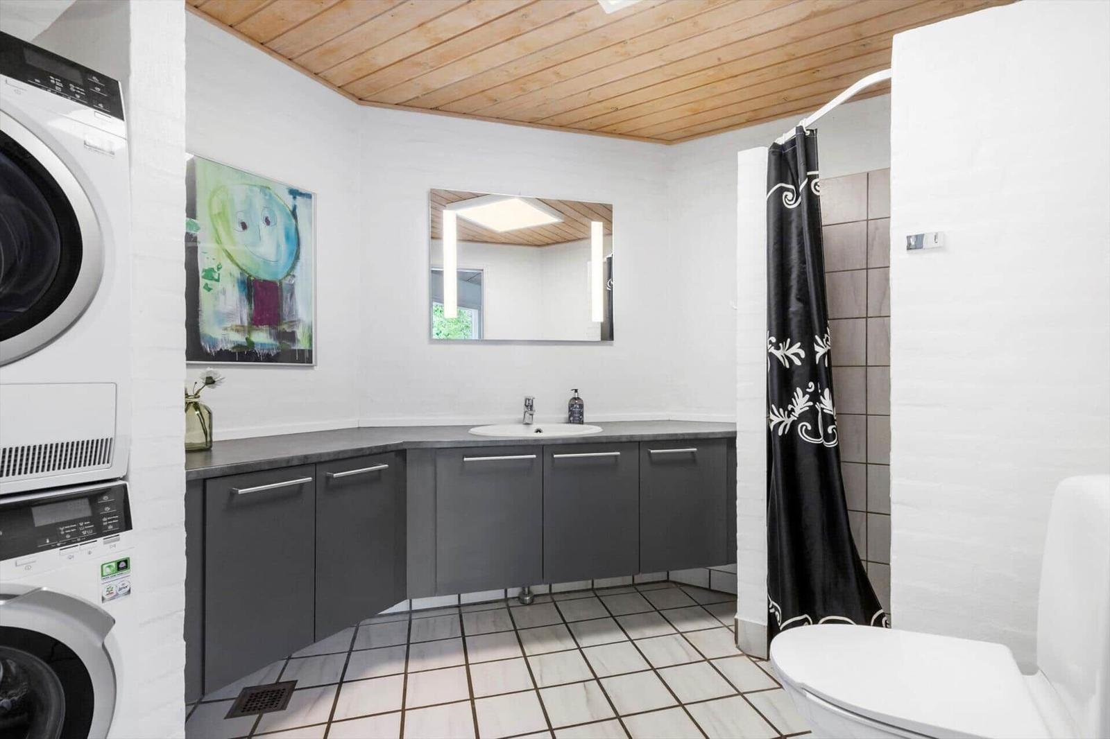 Badezimmer mit Waschmaschine, Dusche und Spiegelschrank.