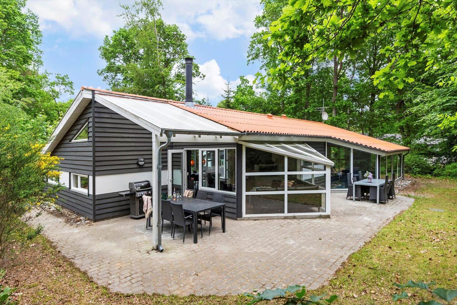 Haus mit Terrasse, Grill und Sitzgelegenheiten im Grünen.
