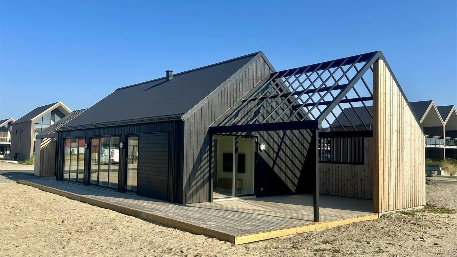 Moderne Strandvilla mit Holzveranda und großzügigen Fenstern.