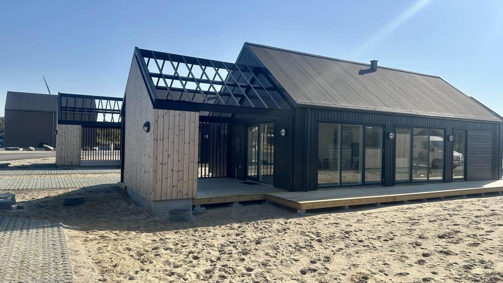 Moderne Strandvilla mit Holzfassade und großzügigem Glasbereich.
