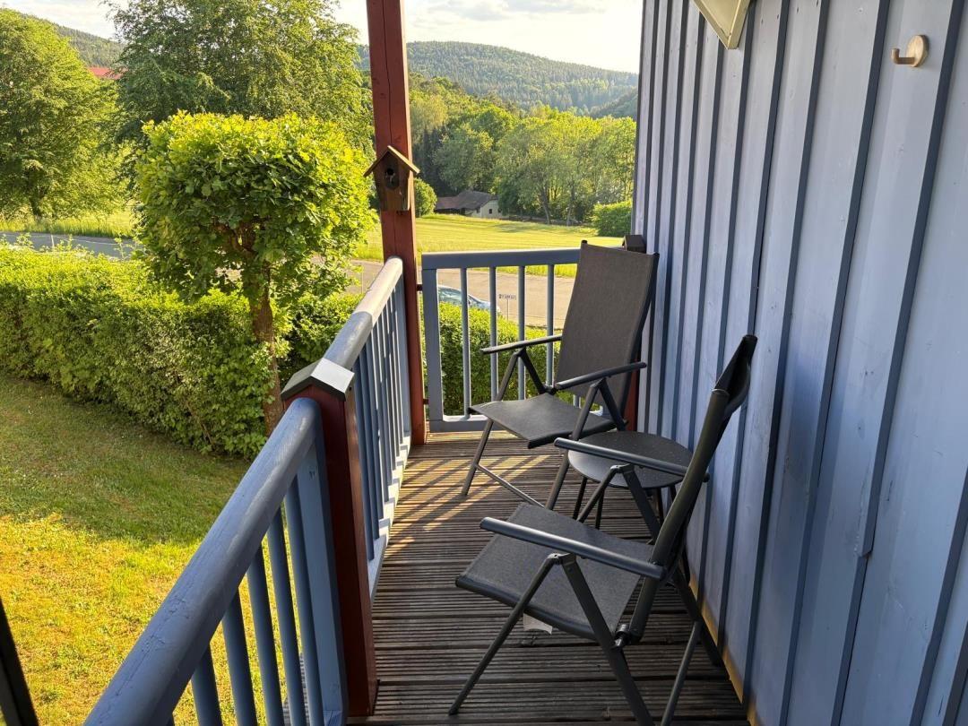 Terrasse mit zwei Stühlen und Blick auf grüne Landschaft.