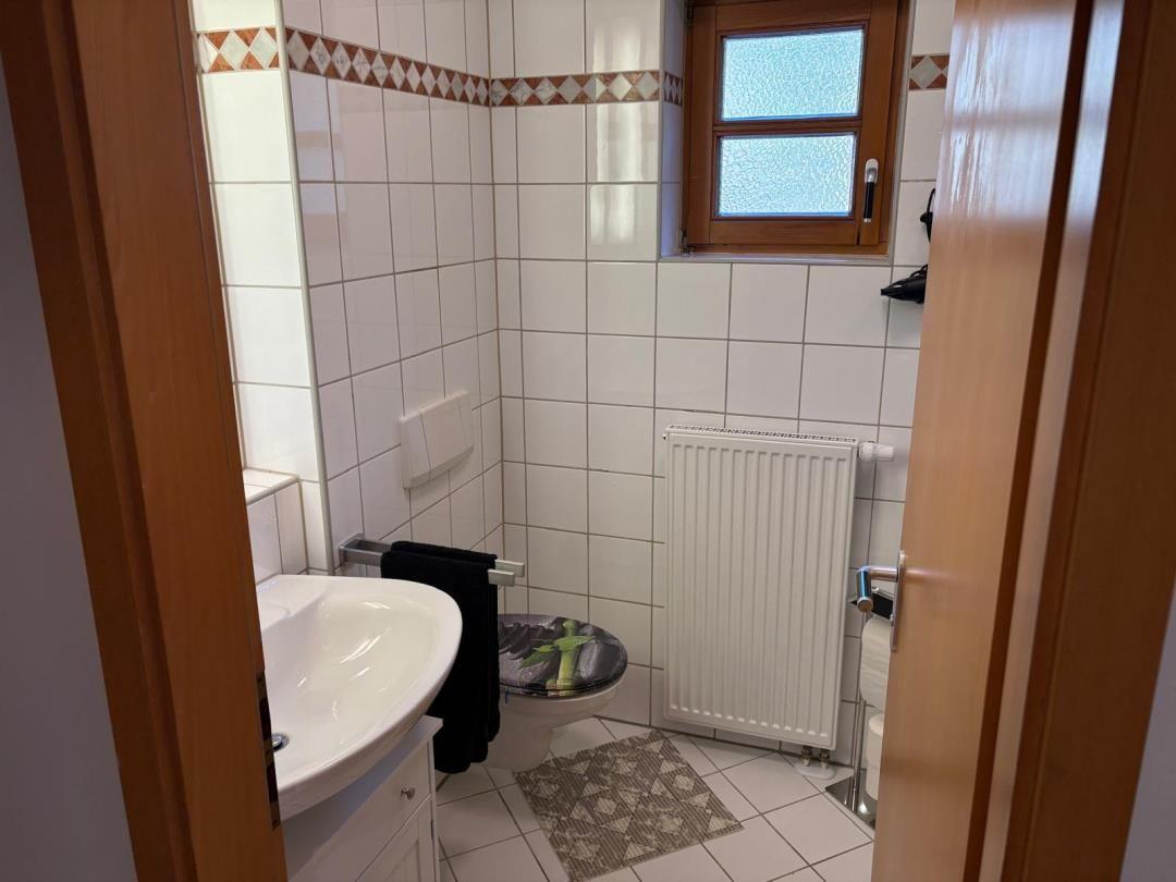 Badezimmer mit Toilette, Waschbecken und Heizkörper an der Wand.
