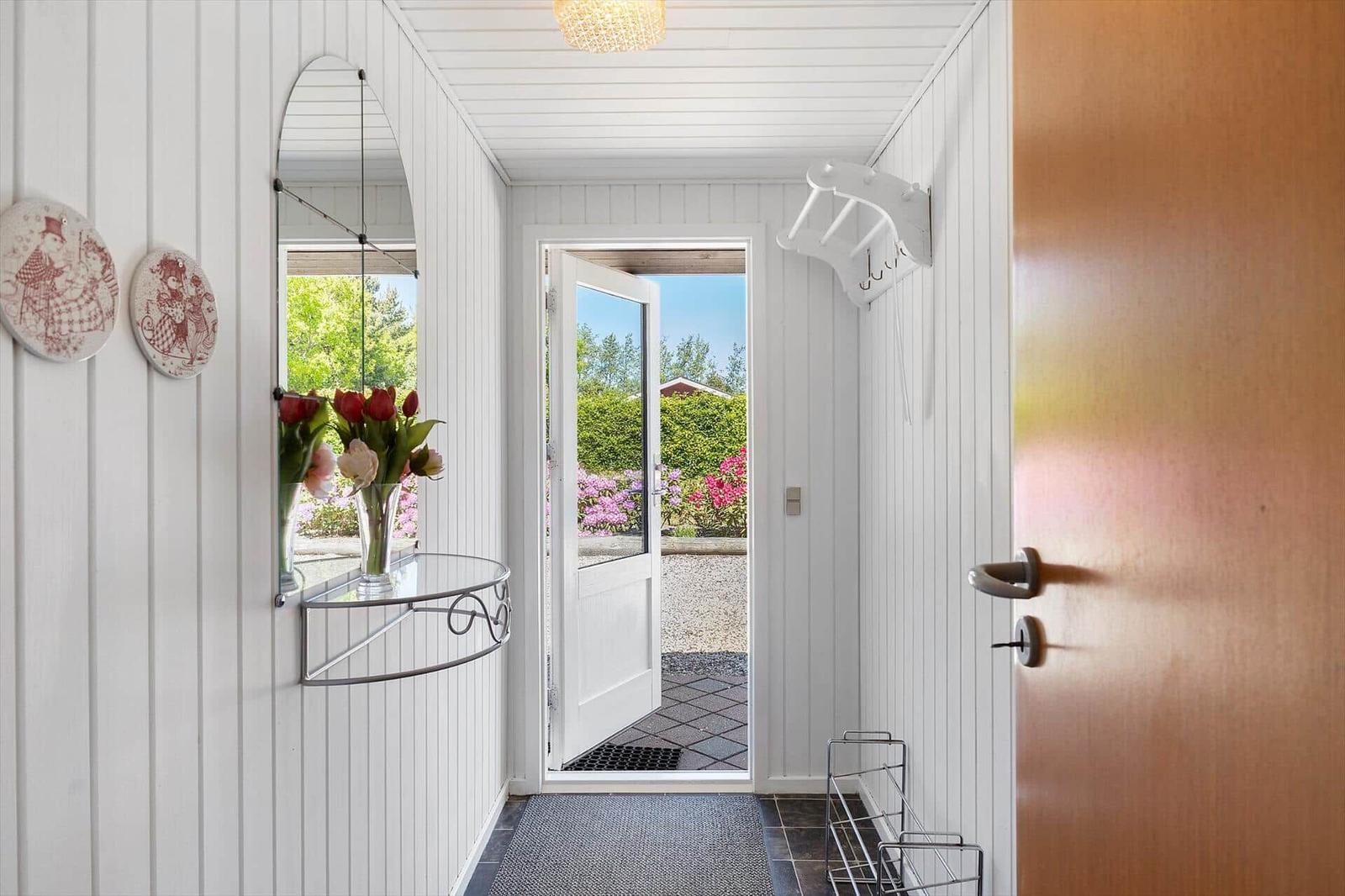 Hausgang mit Spiegel, Blumen und Blick auf Garten