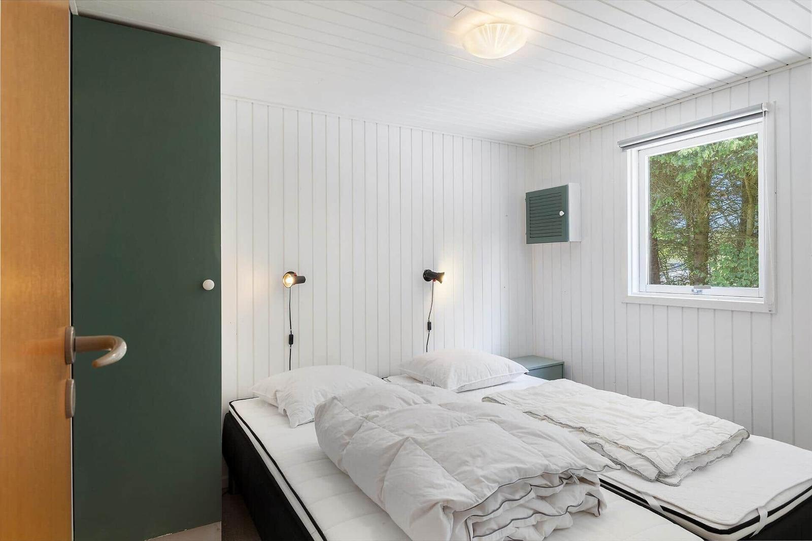 Schlafzimmer mit zwei Betten, Fenster und grüner Tür.