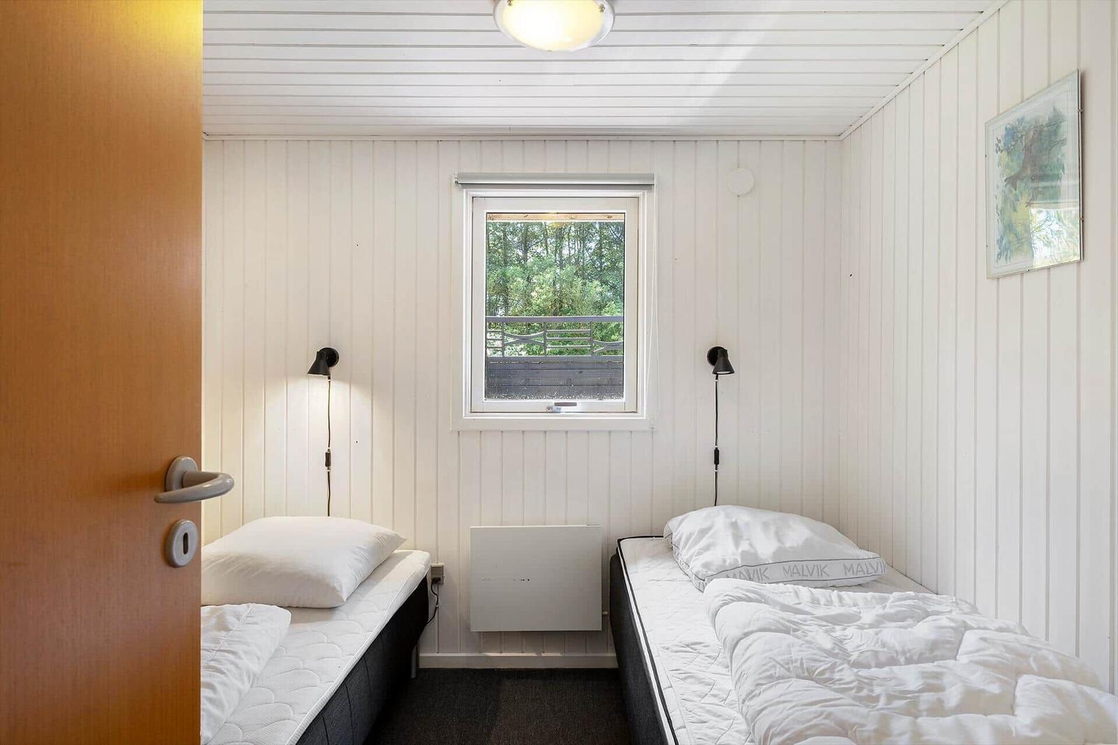 Zwei Einzelbetten in einem Raum mit Fenster und weißen Wänden.