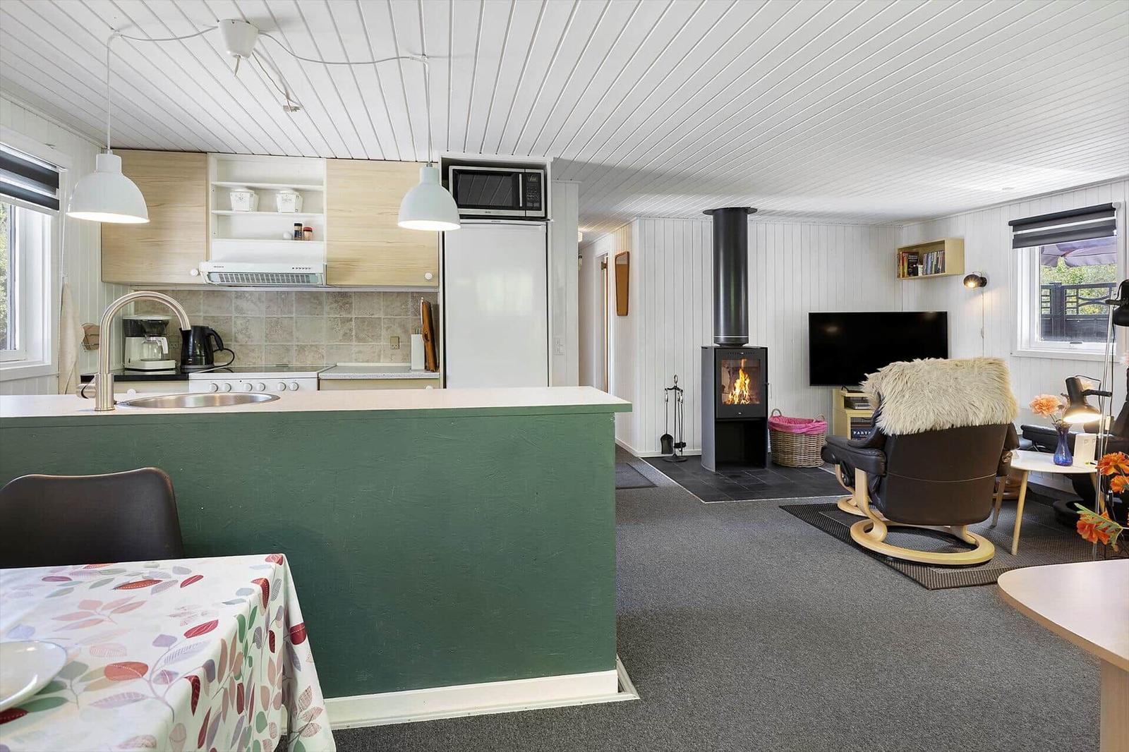 Küche mit Essbereich und Wohnzimmer mit Kamin und TV.