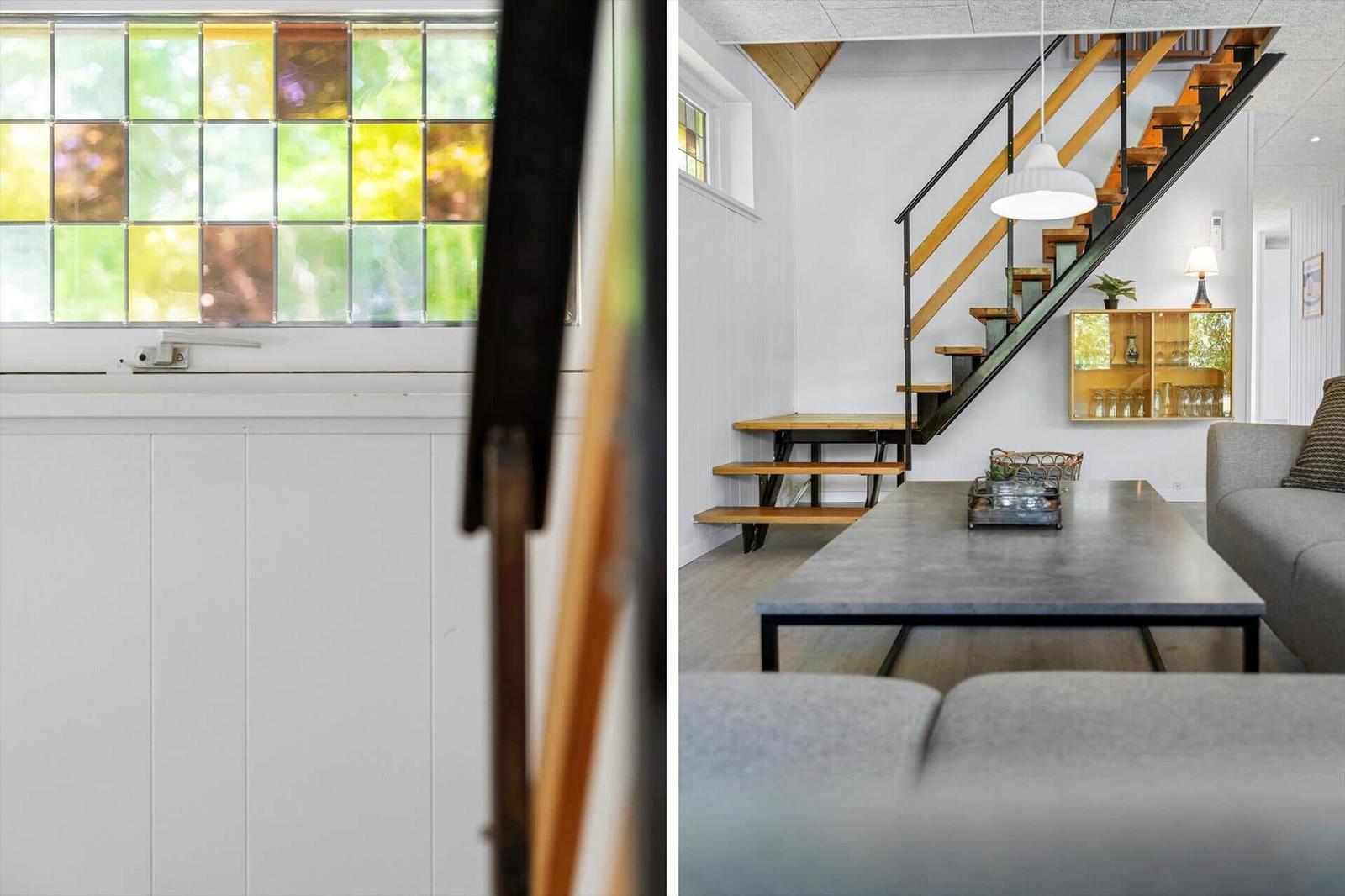 Ein Wohnraum mit Treppe und Fenster mit bunten Glassteinen.