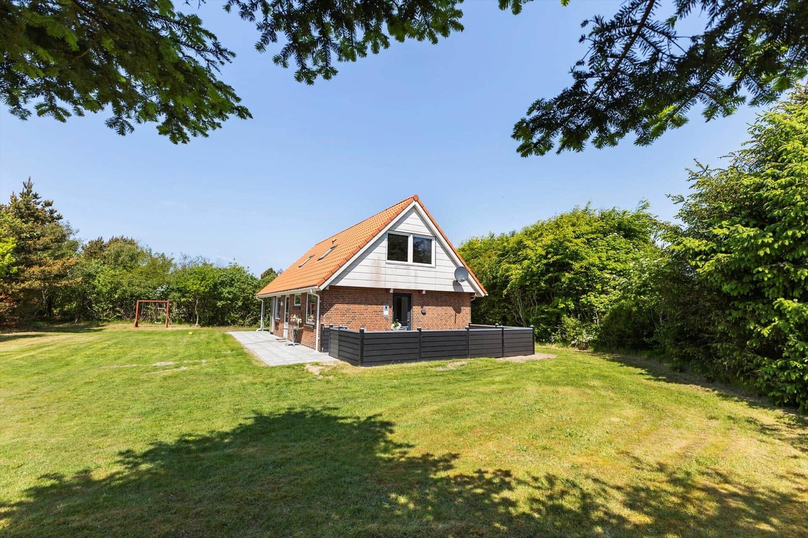 Ein Haus mit rotem Dach und Backsteinfassade steht auf einer grünen Wiese.