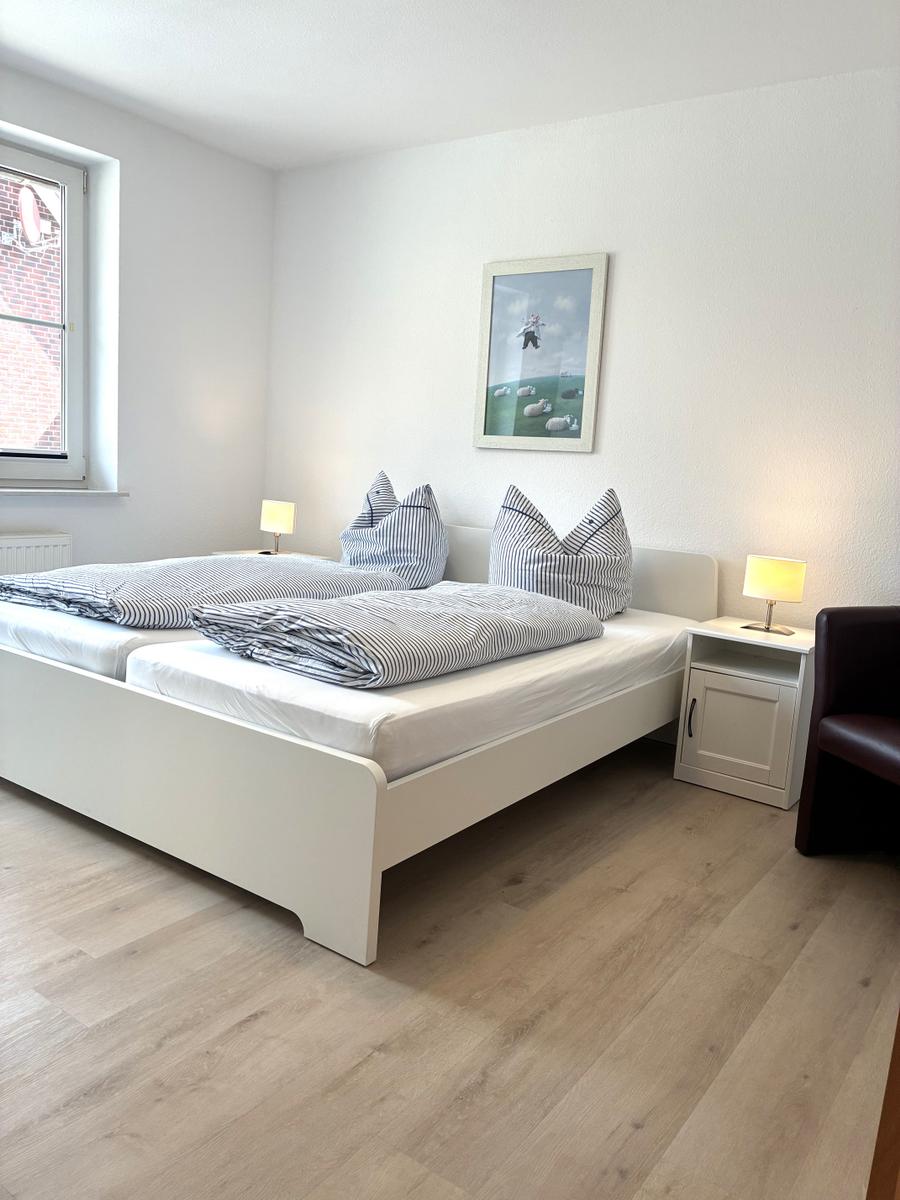 Schlafzimmer mit Doppelbett, zwei Nachttischen und einem Fenster.