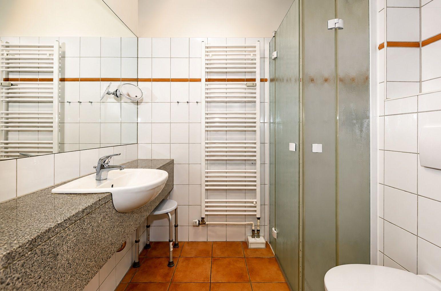 Badezimmer mit Dusche, Waschbecken und Heizkörper