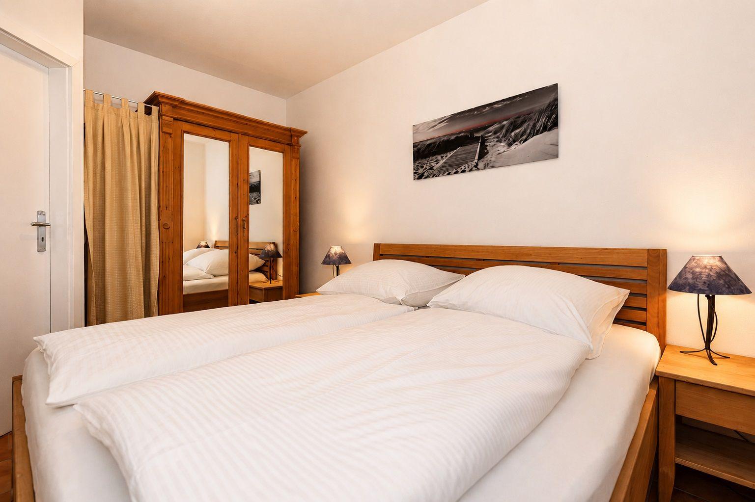Schlafzimmer mit Doppelbett, Holzmöbel und Wandbild.