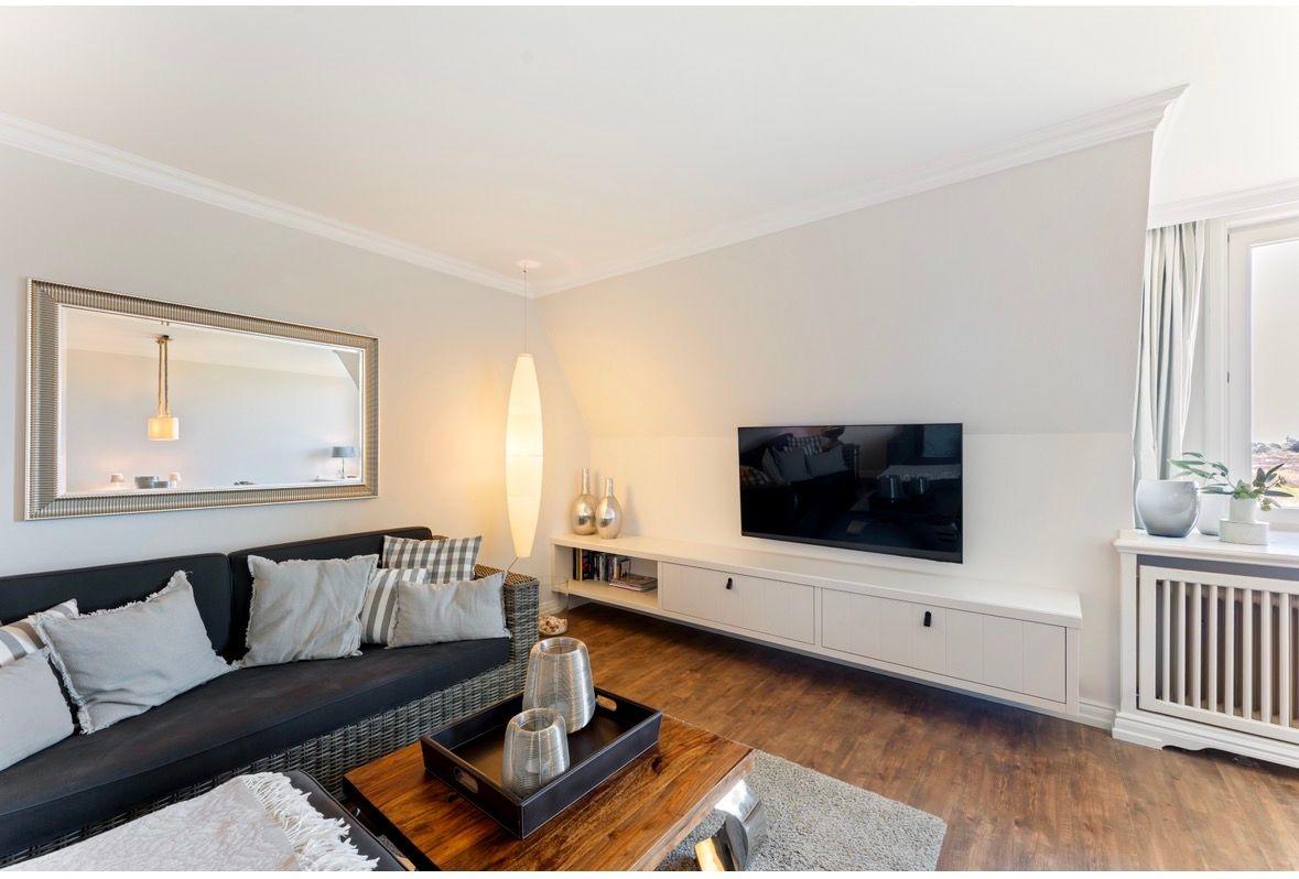 Wohnzimmer mit Sofa, Fernseher und Holzboden