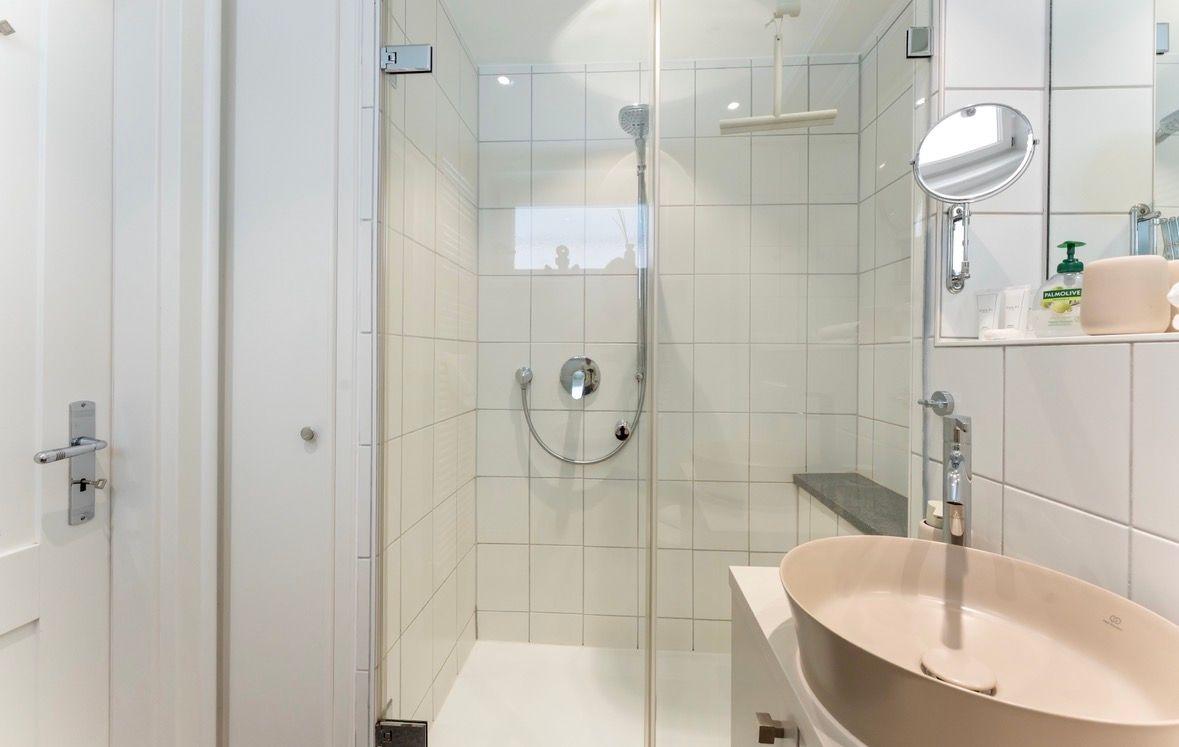 Dusche mit Duschbrause und Waschbecken mit Spiegel