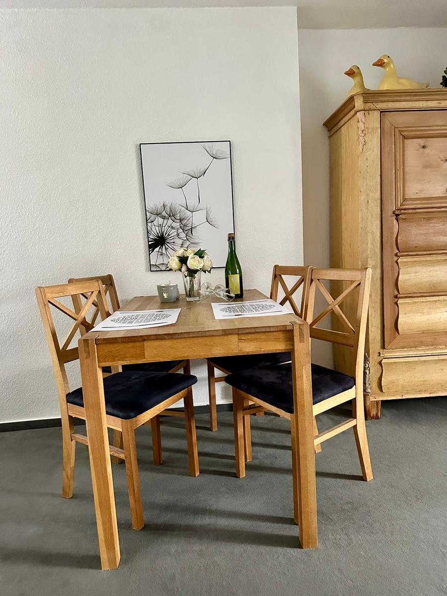 Holztisch mit vier Stühlen, Wandbild und Küchenbuffet im Esszimmer.