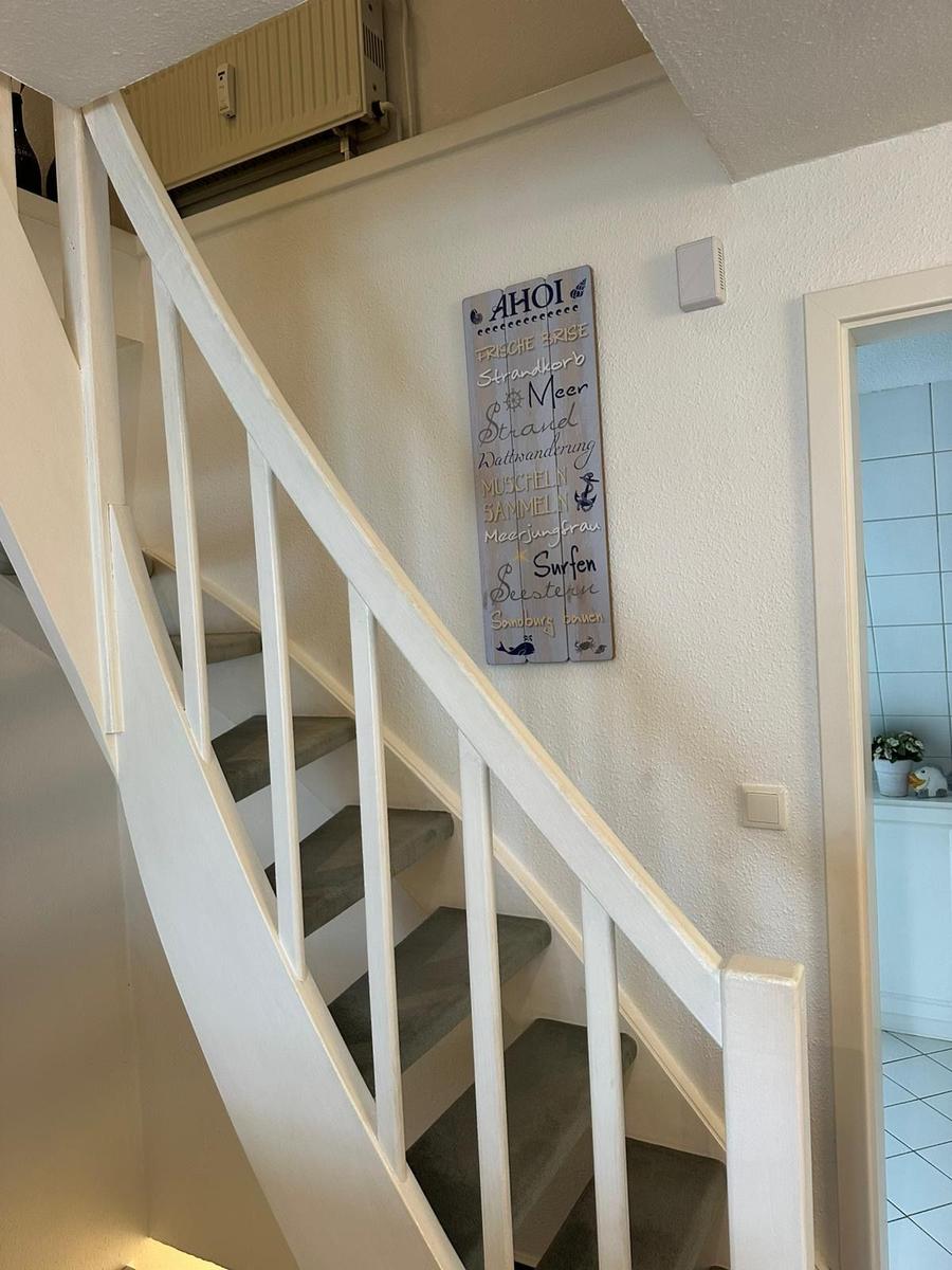 Treppenhaus mit weißer Treppe und Wanddekoration mit Seemotiven.