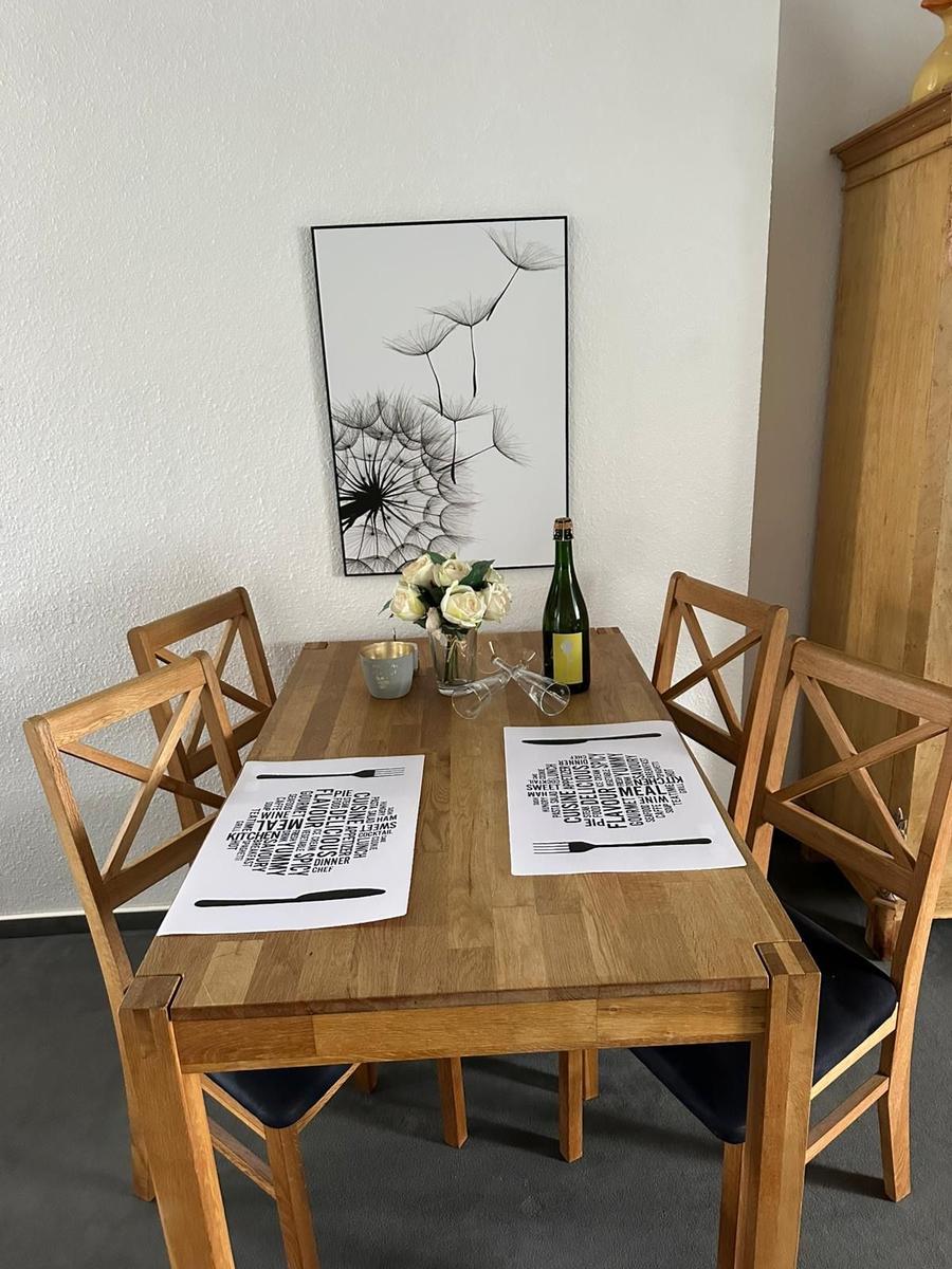Holztisch mit vier Stühlen, Blumen und Platten auf Tisch