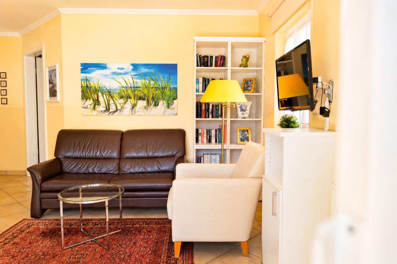 Ein Wohnzimmer mit braunem Sofa, weißem Sessel und Glas-Tisch auf Teppich.