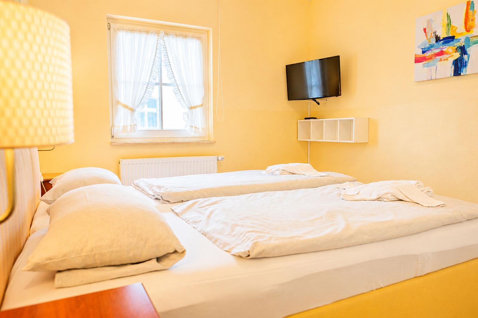 Ein Schlafzimmer mit einem Bett, einem Fenster, einer TV-Wand und einer Wanddekoration.