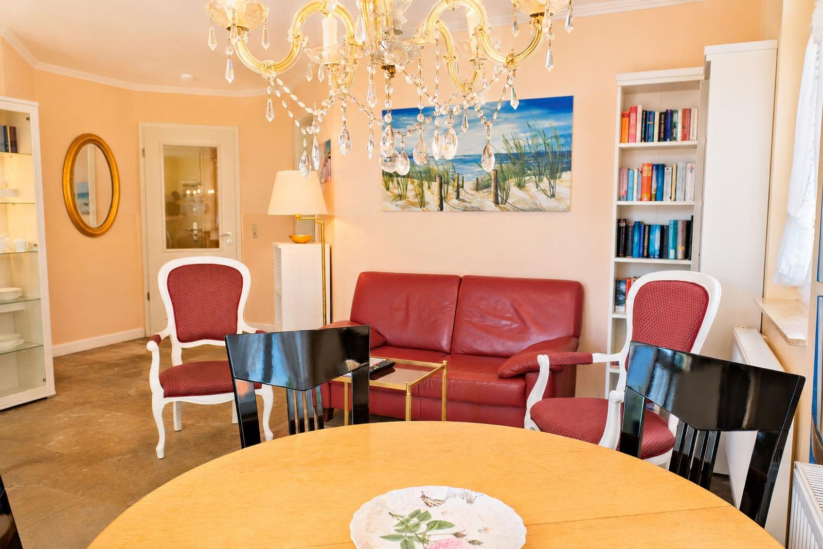 Ein Raum mit rotem Sofa, Essbereich und Kronleuchter.