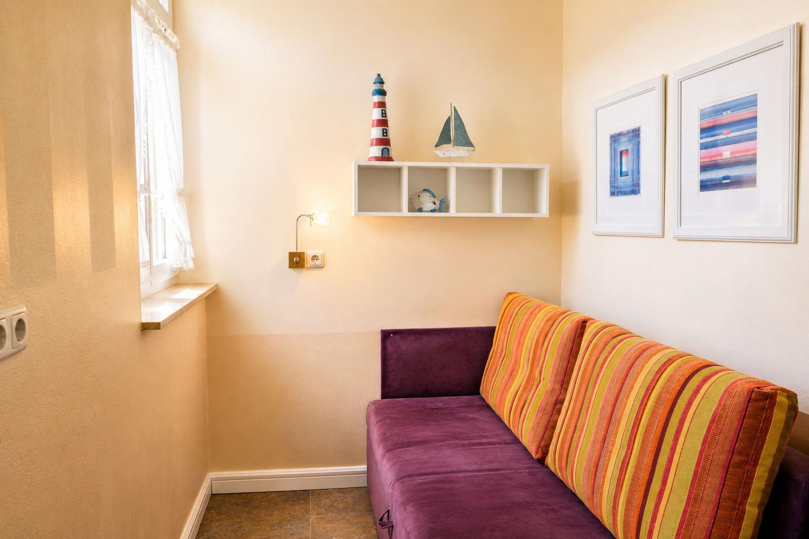 Ein Sofa mit gestreiftem Rückenlehnenkissen und Wandregal mit Dekoration.