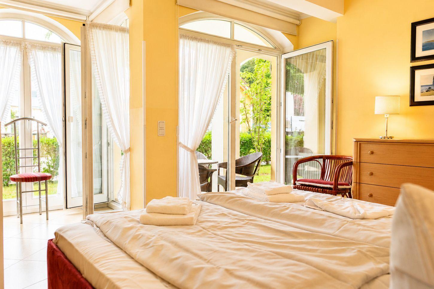 Schlafzimmer mit Bett, Schrank und Blick auf Balkon mit Garten.