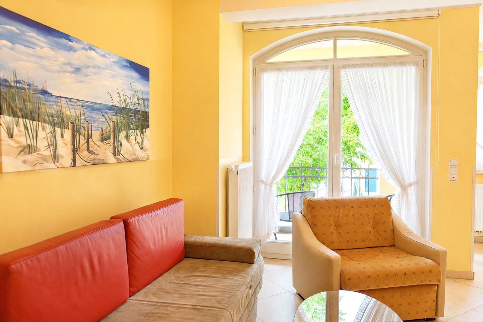 Wohnzimmer mit rotem Sofa, gelben Wänden und Blick auf Balkon