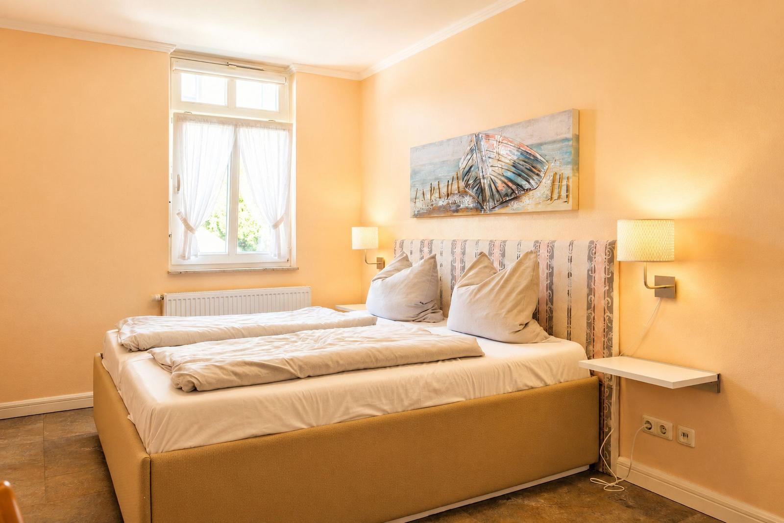 Schlafzimmer mit Bett, Fenster und Wandbild.