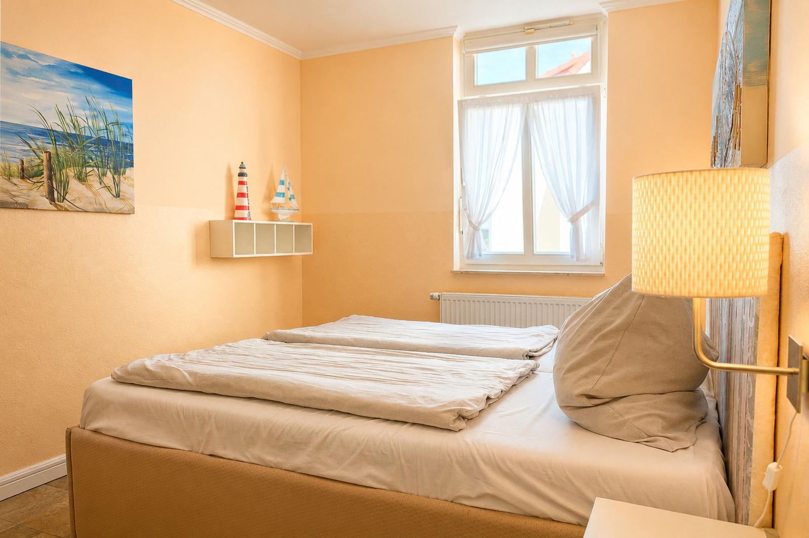Schlafzimmer mit Bett, Fenster und Wandbild. Lampe und Dekoration an der Wand.