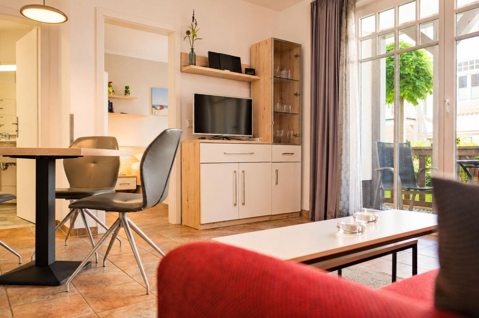 Wohn- und Essbereich mit TV, Schränken und Blick auf Balkon