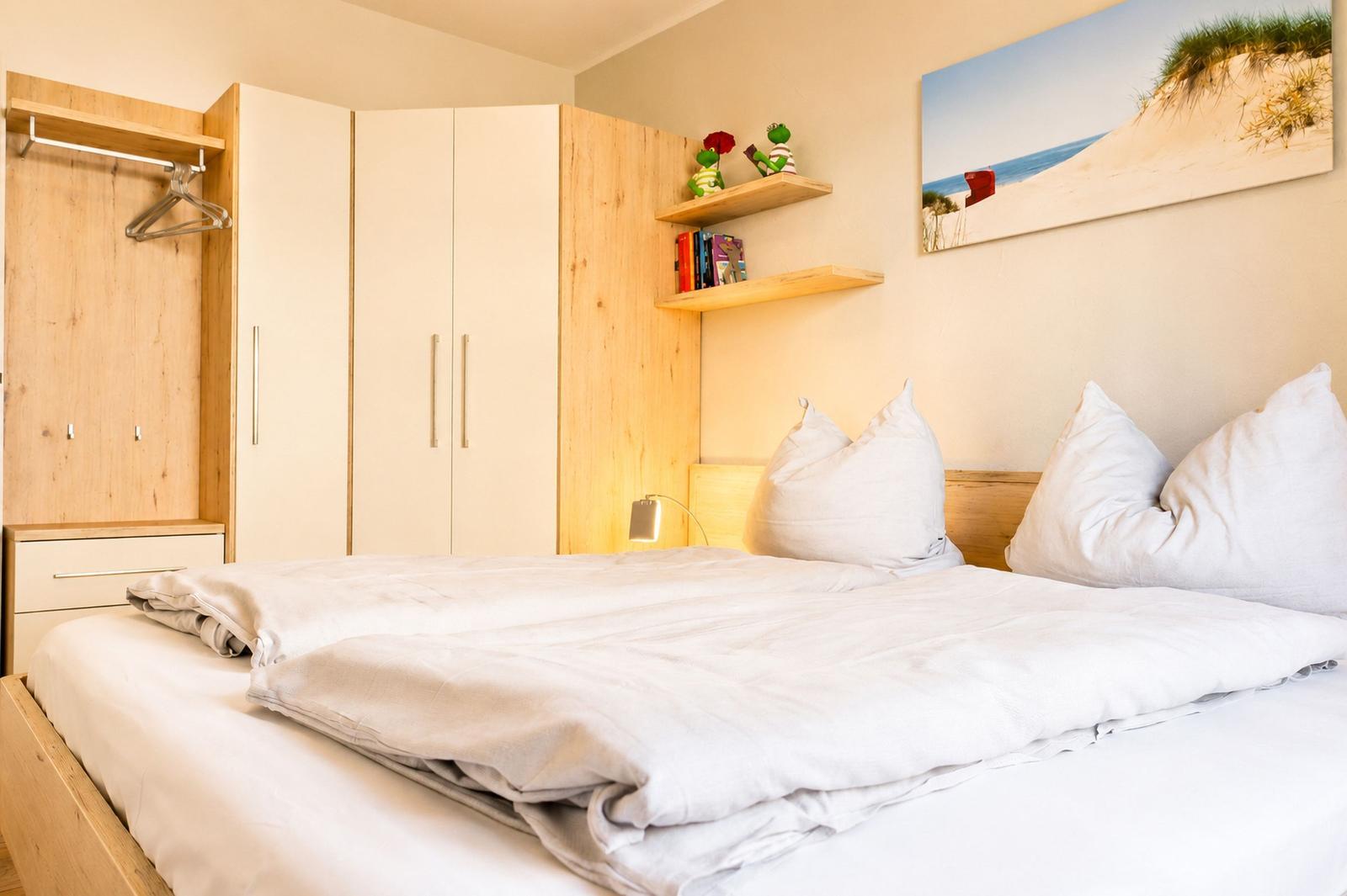 Schlafzimmer mit Bett, Kleiderschrank und Wandbild