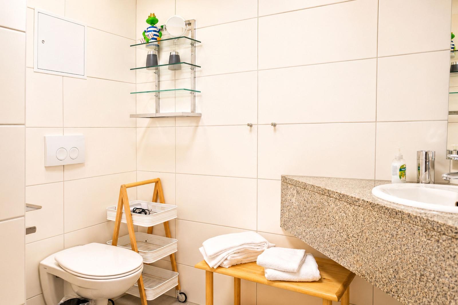 Badezimmer mit Toilette, Waschtisch und Handtuchständer.