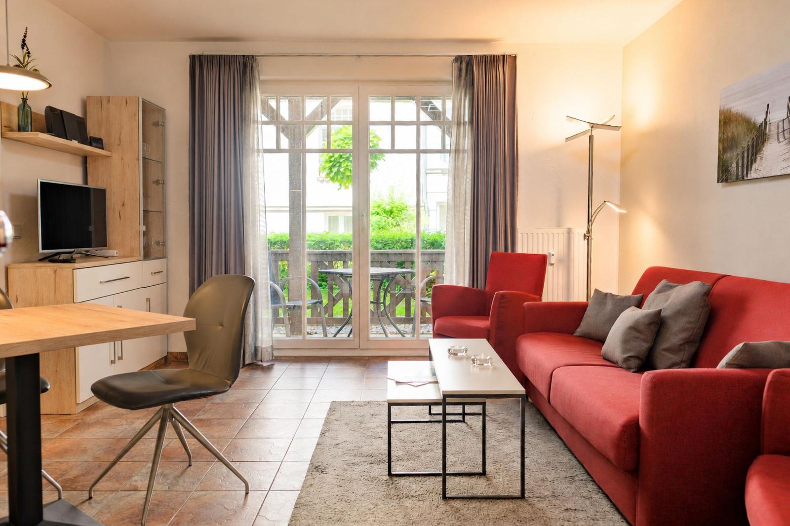Wohnbereich mit rotem Sofa, Couchtisch und Blick auf Balkon