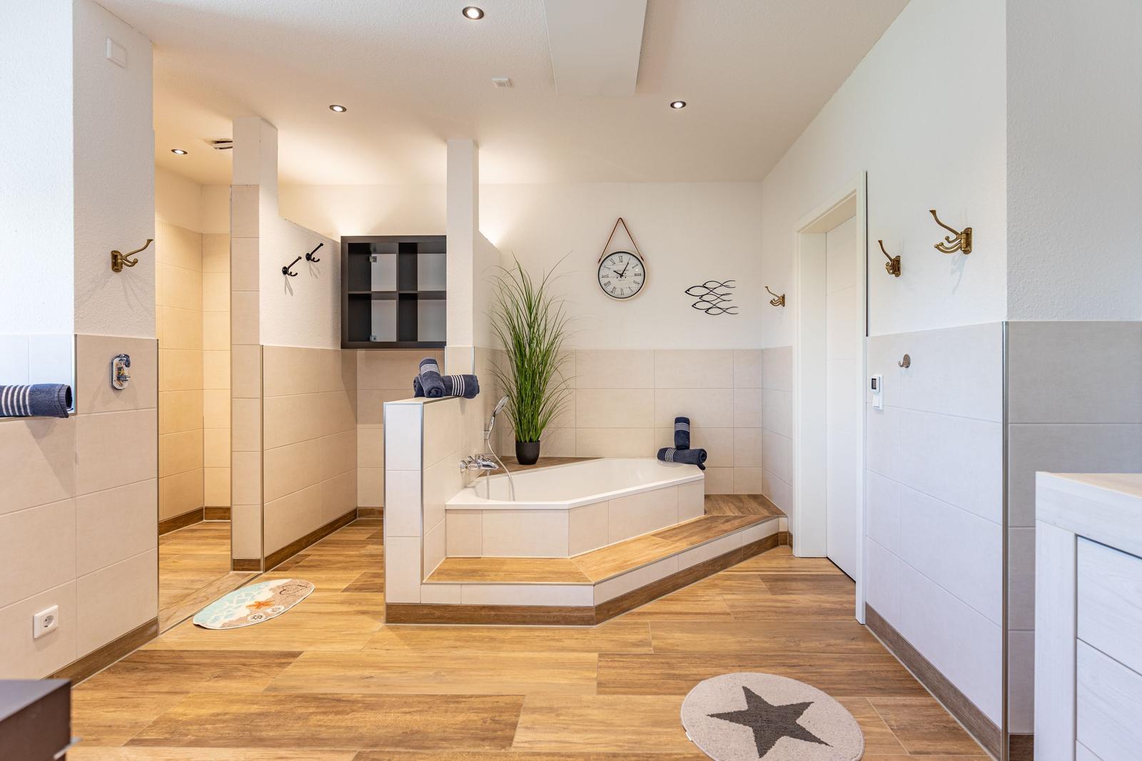 Bad mit Badewanne, Pflanze, Wanduhr und Holzboden