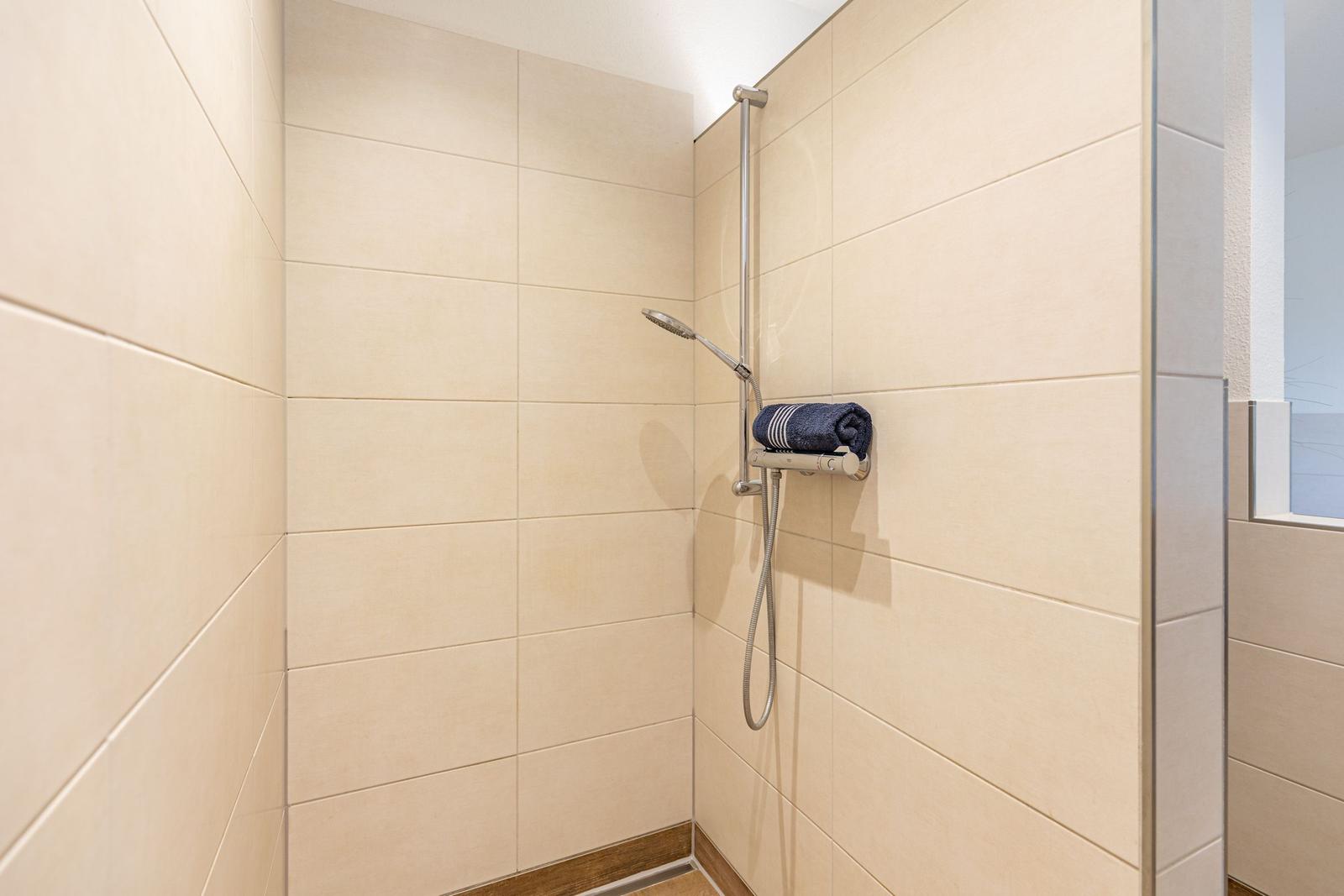 Dusche mit Handbrause und Handtuchhalter an Wand