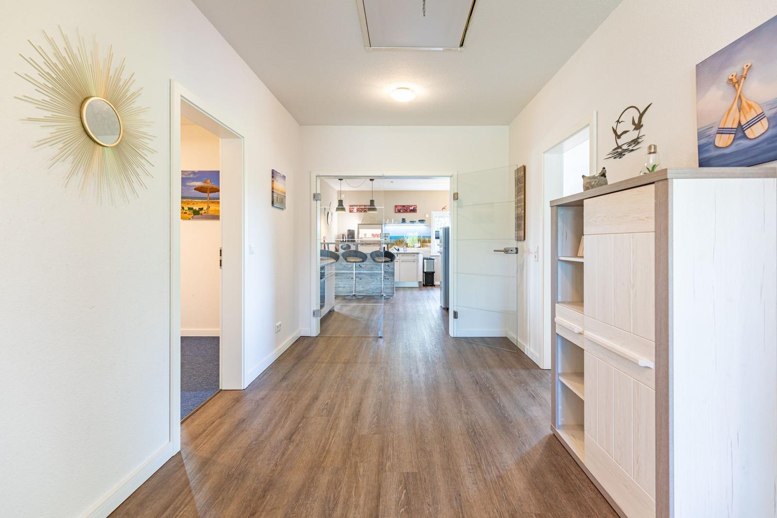 Hallenflur mit Holzboden, Schrank und Spiegel. Durchgänge zu Küche und Schlafzimmer.