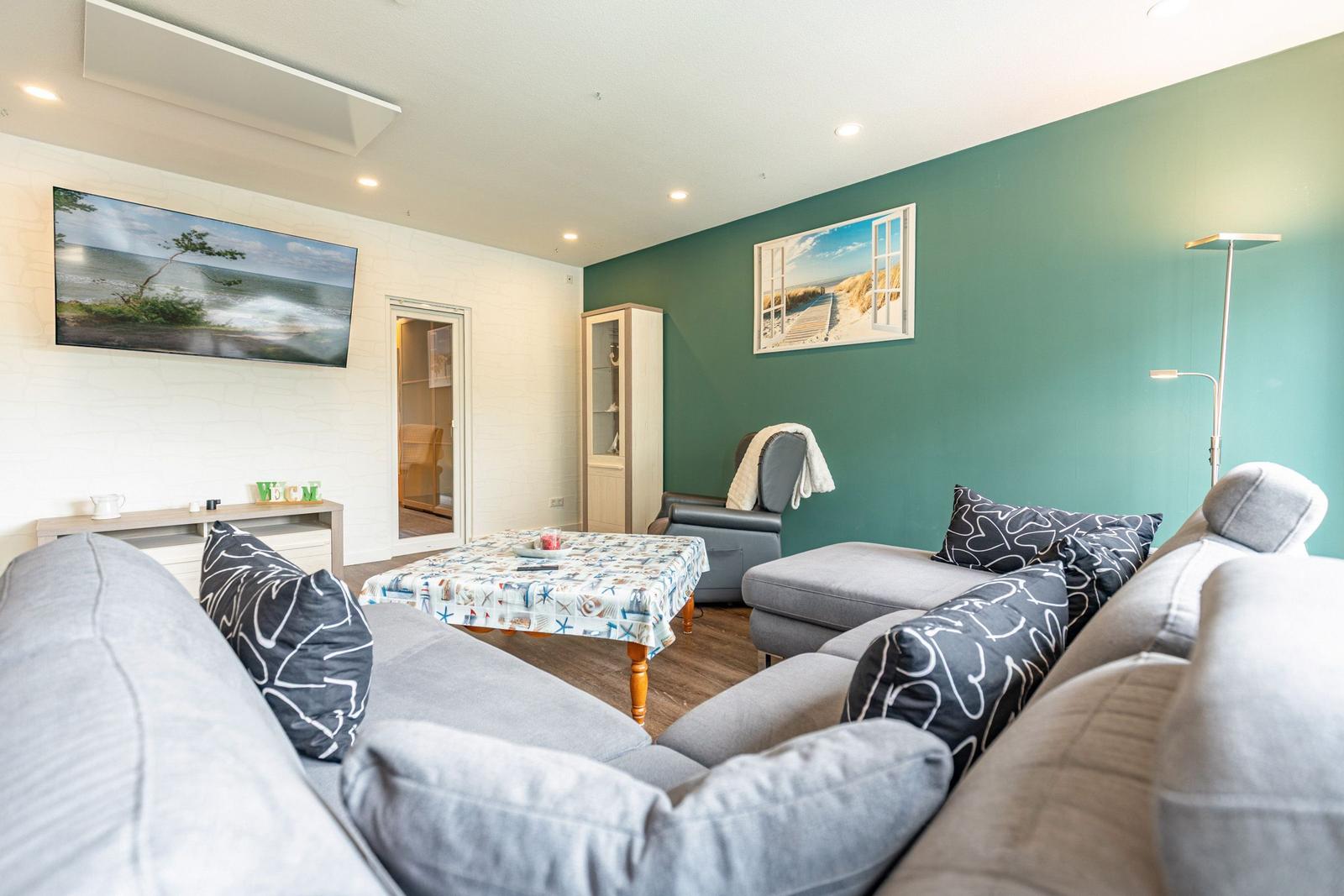 Wohnzimmer mit Sofa, Couchtisch und Fernseher an der Wand.