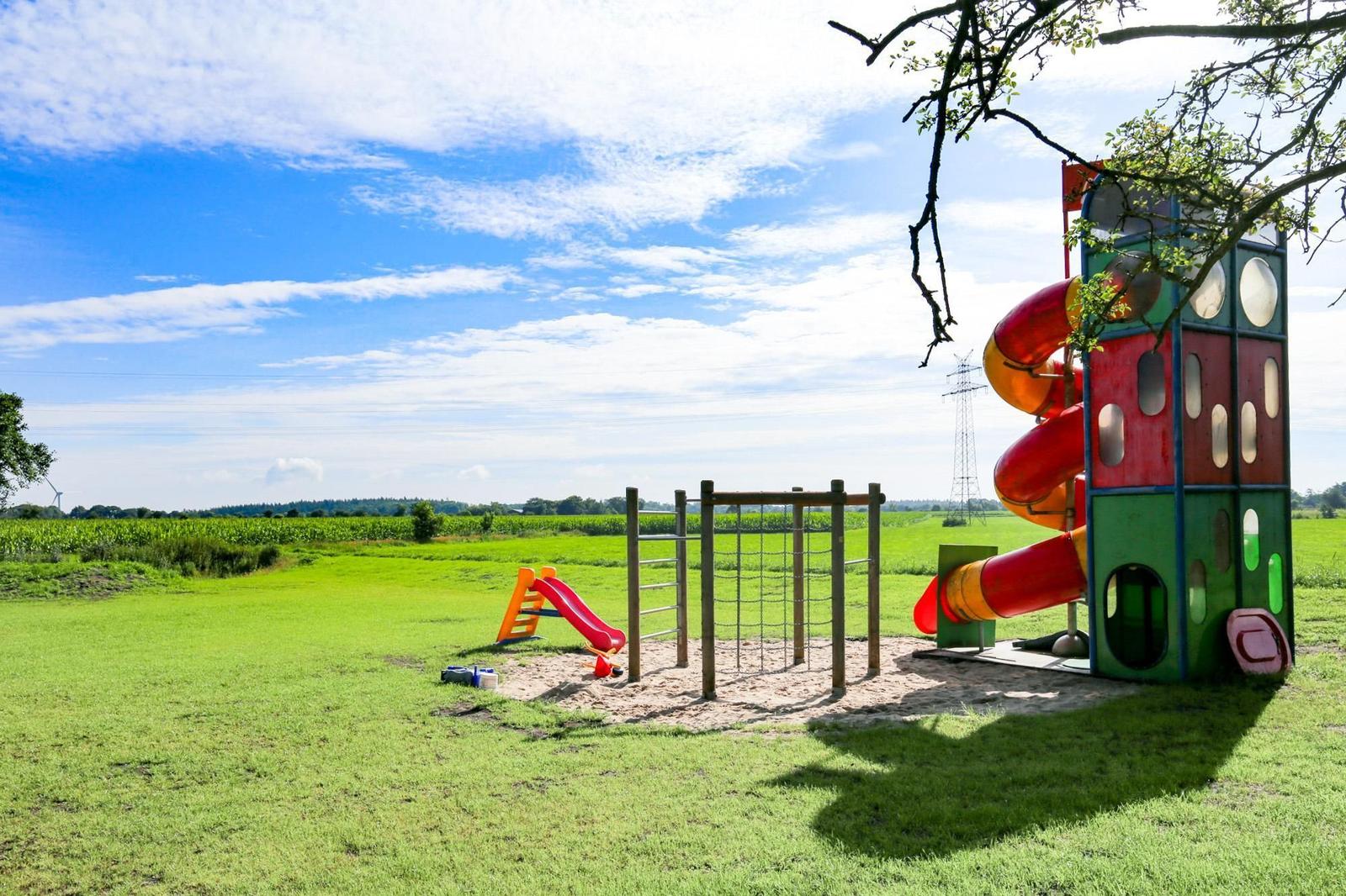 Kinderbereich mit Rutsche und Klettergerüst im Gras.
