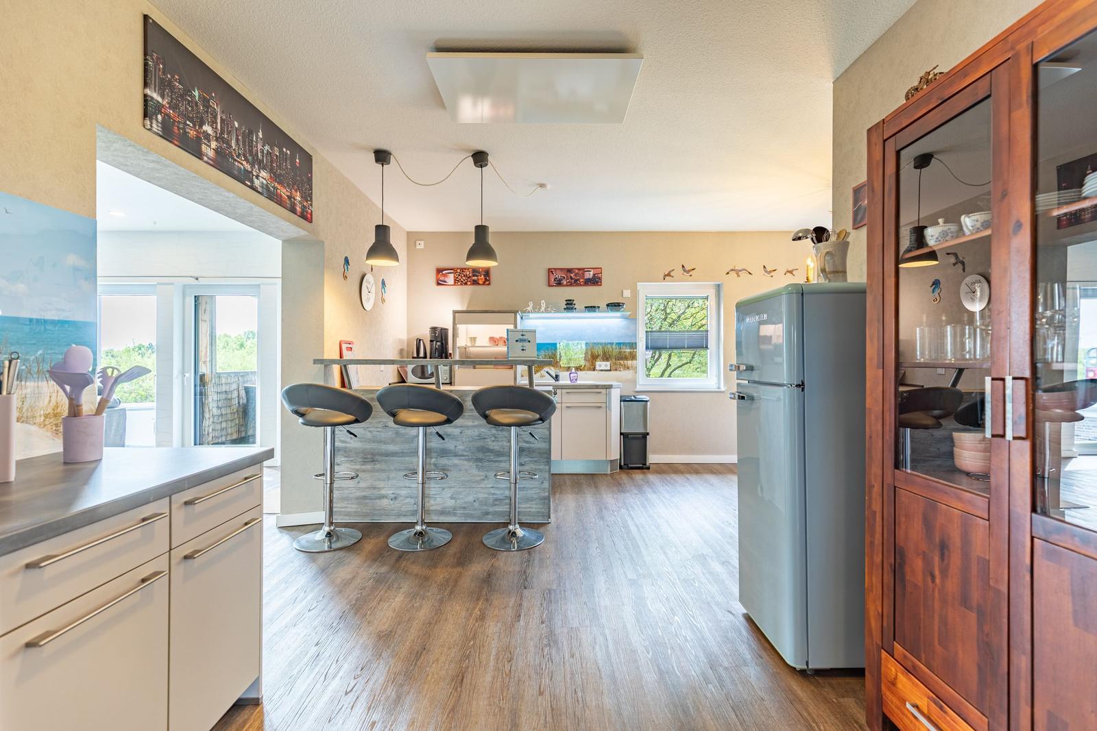 Küche mit Barhocker, Kühlschrank und Glasvitrine