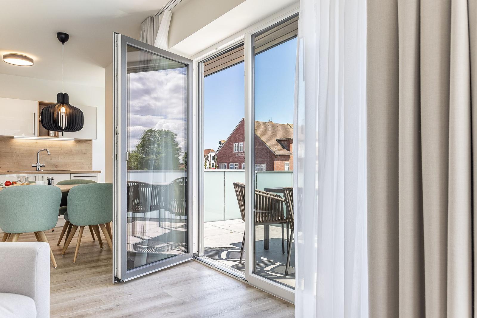 Terrasse mit Sitzgruppe und Blick auf Wohnhaus. Küchenbereich mit Esstisch und Stühlen.
