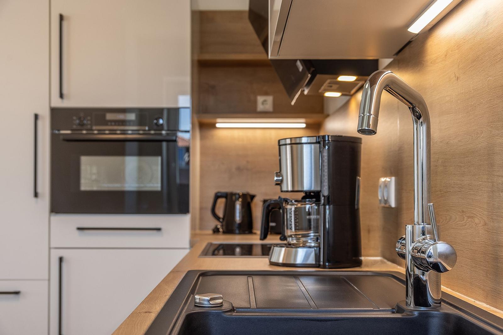 Küche mit Spüle, Kaffeemaschine, Herd und Backofen.