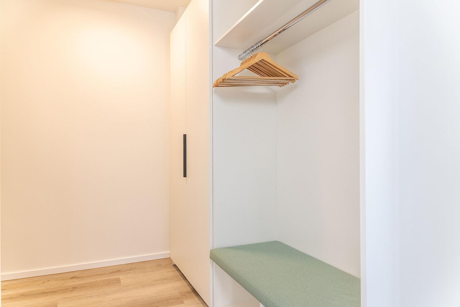 Schrank mit Kleiderständer und Sitzbank in einem Schlafzimmer