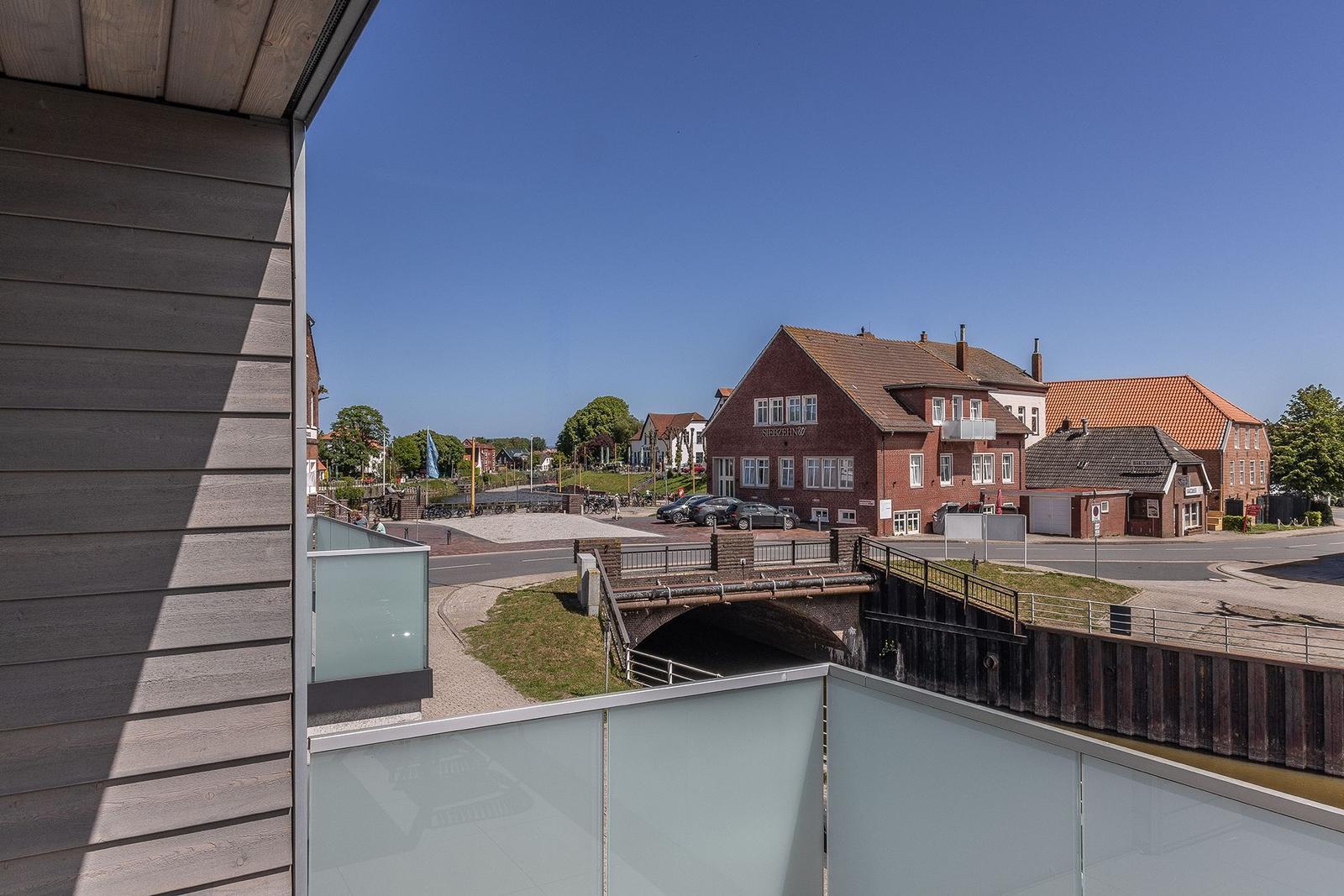 Blick von Balkon auf Kanal und rote Backsteinhäuser unter blauem Himmel.