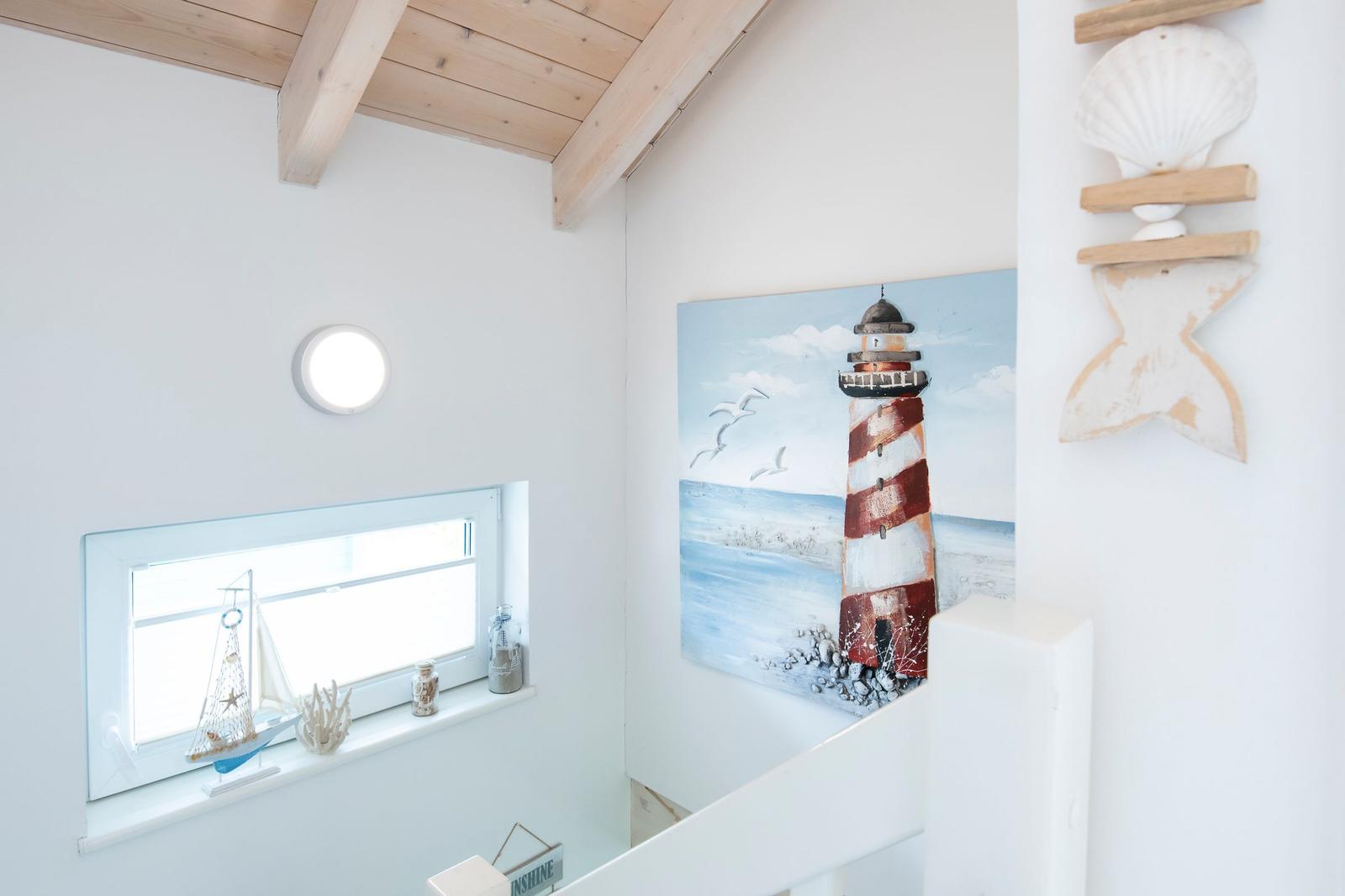 Wohnbereich mit Holzdecke, Seemotiv-Bild und Fenster mit Segelboot.