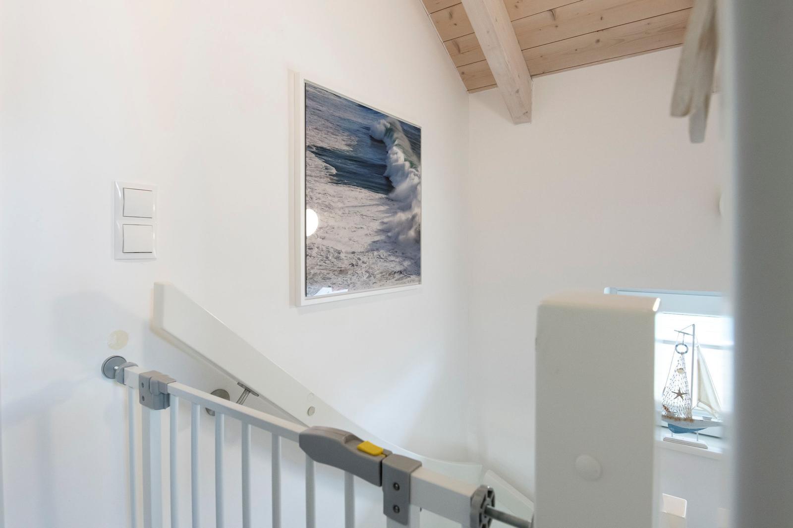 Treppenhaus mit Baby-Sicherheitsgeländer und Wandbild von Wellen.