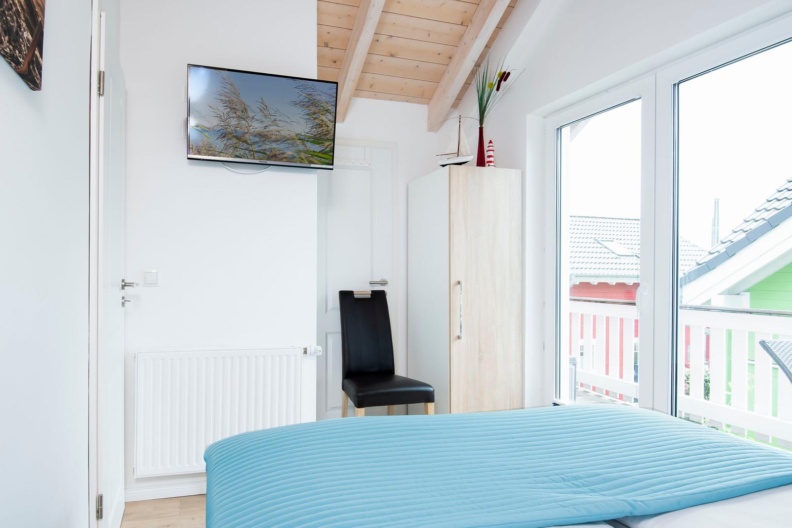 Schlafzimmer mit Bett, TV und Balkonansicht