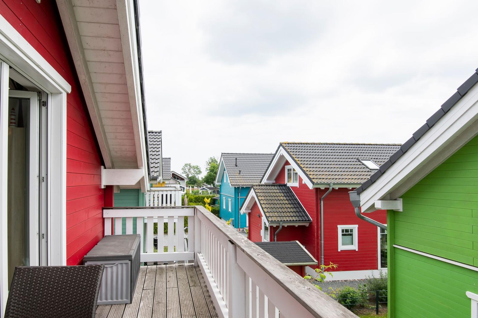 Terrasse mit Blick auf bunte Häuser und Garten.