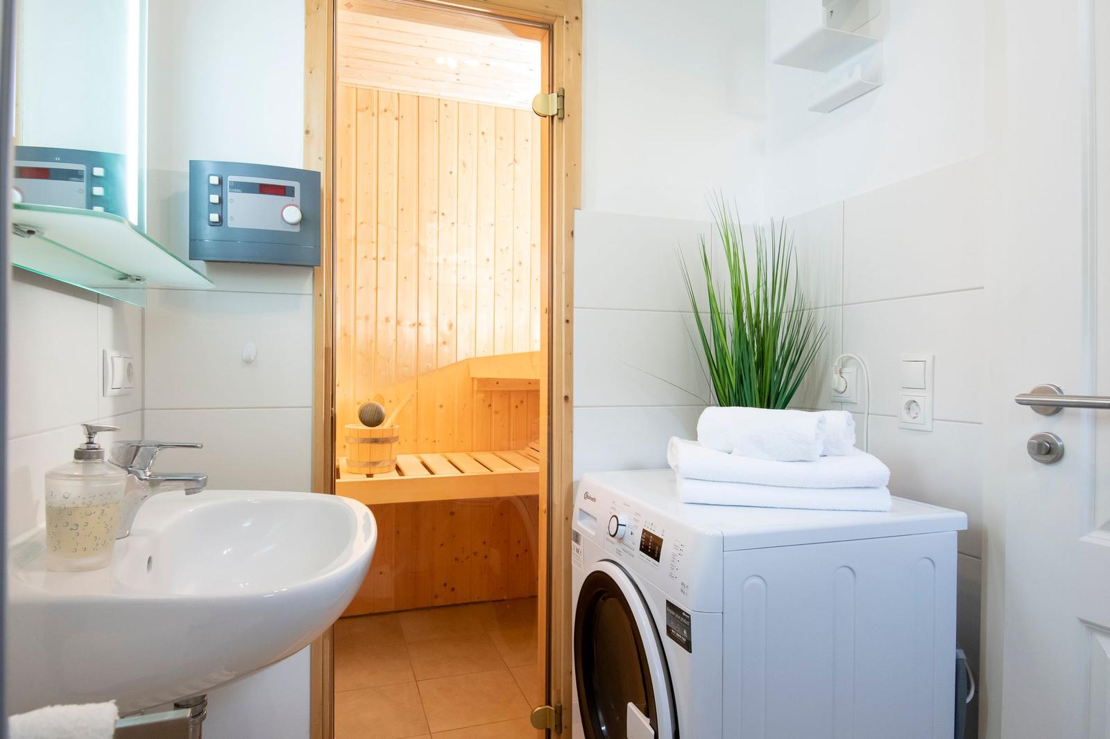 Badezimmer mit Waschmaschine, Sauna und Pflanze.