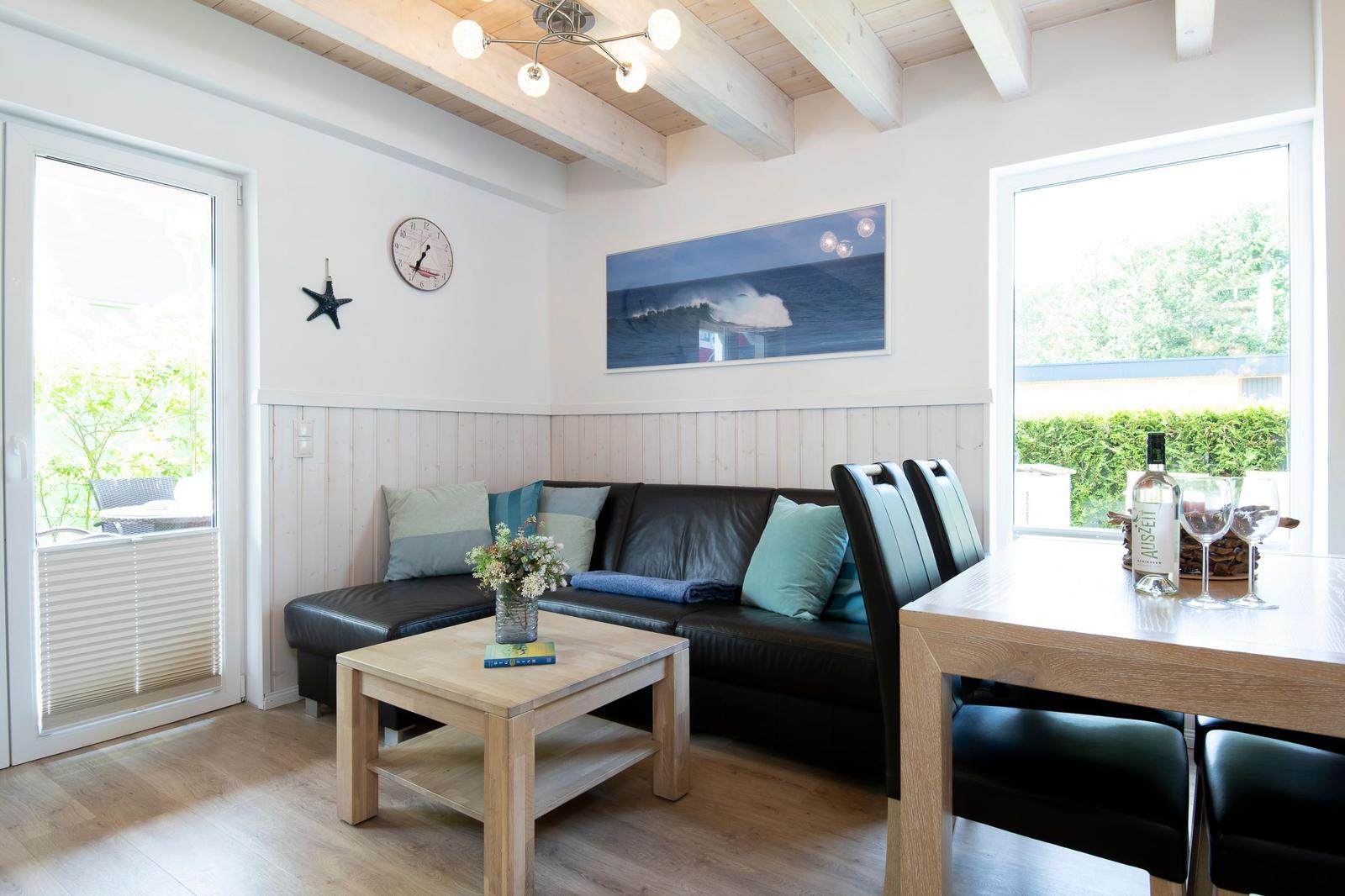 Wohn- und Essbereich mit Sofa, Tisch und Fenstern. Holzdecke und Wandverkleidung.