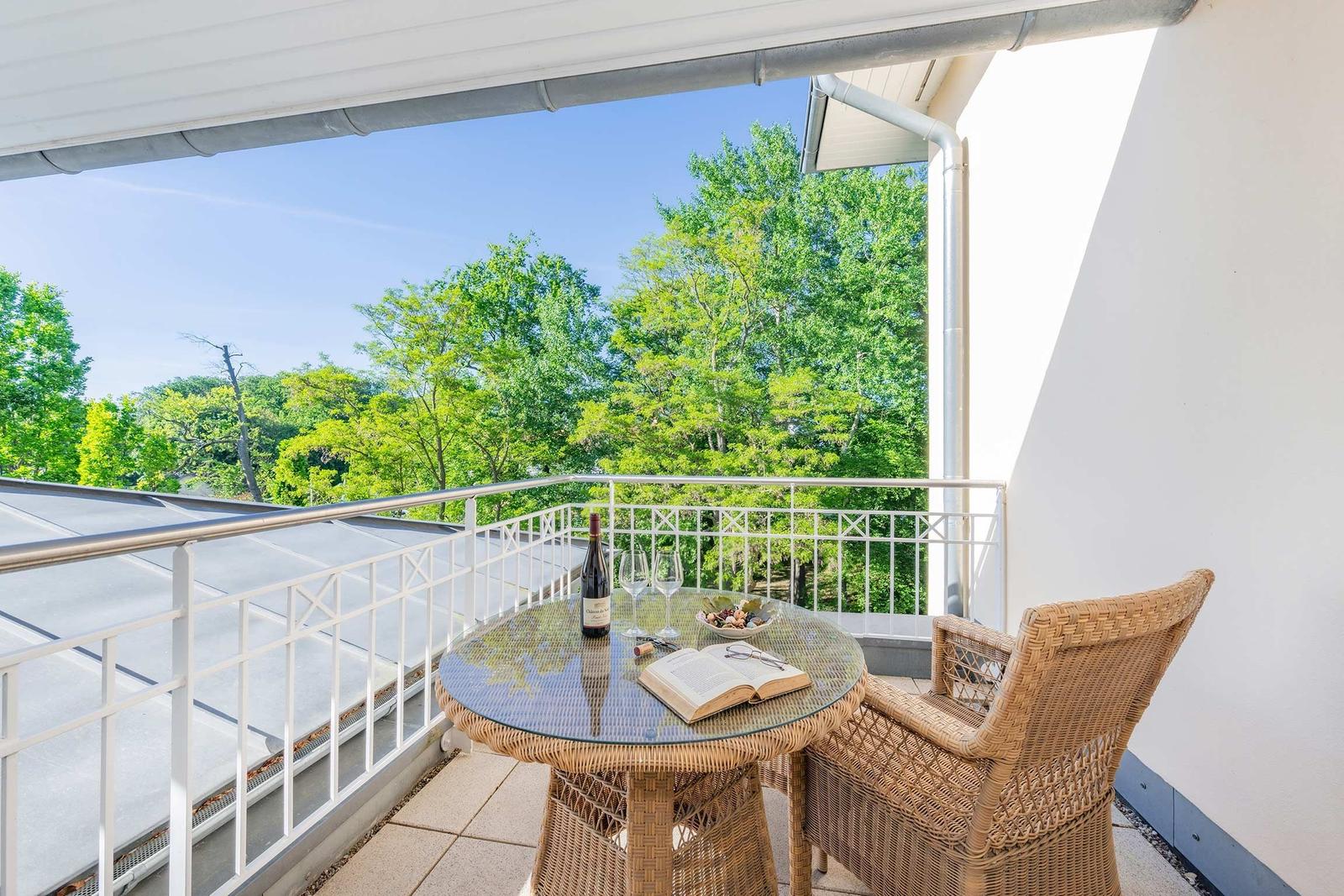 Terrasse mit Tisch, Stühlen und Blick auf Bäume.